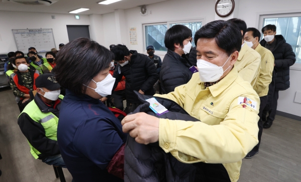 황인호 동구청장(가운데 오른쪽)이 재활용선별장을 방문해 자활사업자에게 방한복 입혀주는 모습